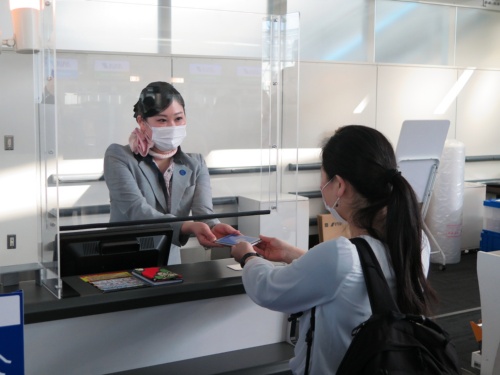 羽田空港で実施した実証実験の様子。コモンパスのデジタル証明書の画面を表示し、チェックインカウンターで係員に示す