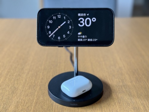 充電中のiPhoneを横向きにした状態で画面をロックするとスタンバイ機能が起動し、ロック画面に情報が表示される。写真では筆者がこれを機に購入したMagSafe充電対応のスタンドを使用している。台の部分ではAirPodsも充電できる