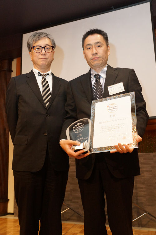 写真1●大賞を受賞したキューデンインフォコムを代表して、同社の松井 克仁ITコンサルティング部長がトロフィーと表彰状を受け取った